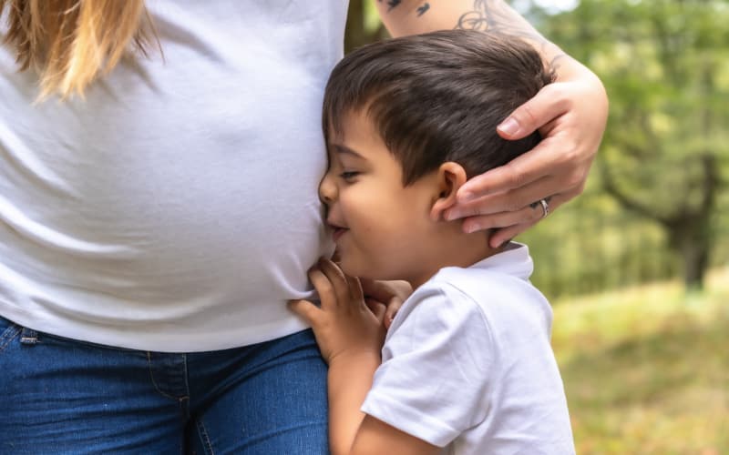 A young boy hugs his pregnant mother